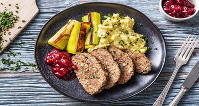 Kruidig gehaktbrood met gesmoorde prei, aardappelpuree en cranberrychutney
