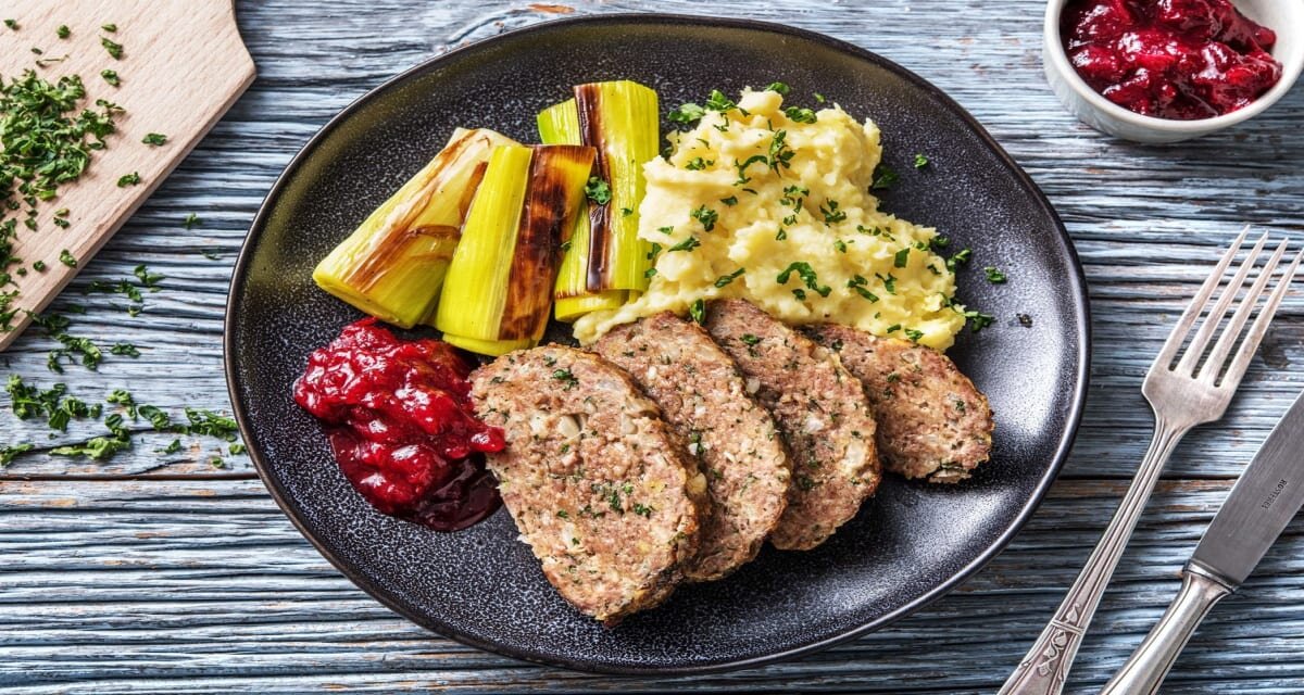 Kruidig gehaktbrood met gesmoorde prei, aardappelpuree en cranberrychutney